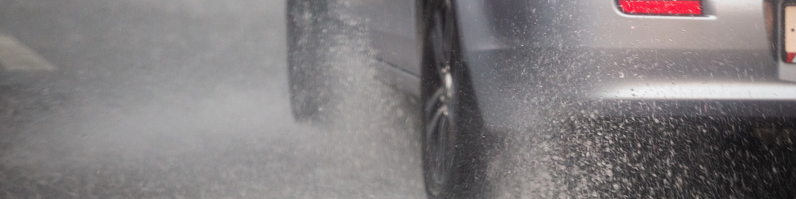 car wheels on road splashing up water