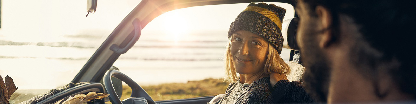 smiling woman and man in parked car by beach